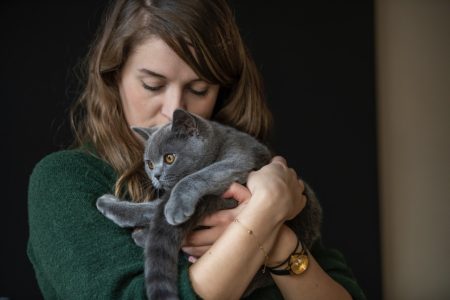 Woman tenderly holding her fluffy gray cat.